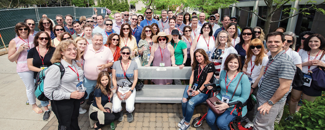 Many people surround a metal bench 